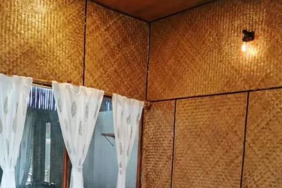 A bedroom with a bed, curtains, and a window.
