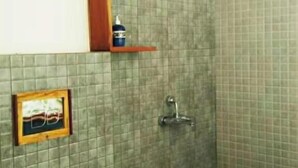 Een badkamer met toilet, douche en een klein schapje met toiletartikelen.