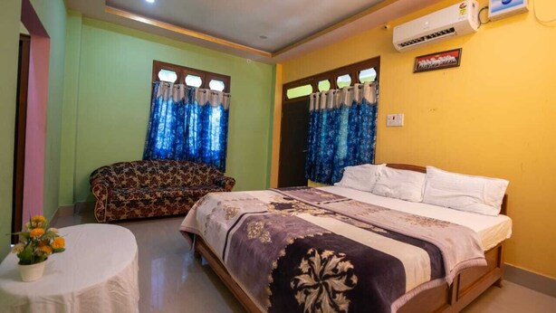 A bedroom with a bed, a sofa, and a small table with flowers. - Rhino Cottage Manas By GRB (Barnagar)