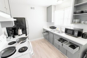 A modern kitchen with a stove, microwave, and cabinets. - Chic 2-Bed Oasis, Sleeps 6! Minutes From Strip! (Las Vegas)