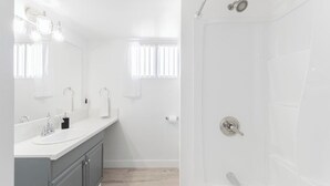 Un baño moderno con tocador doble, ducha e inodoro.