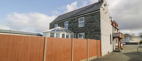 A residential building with a stone facade, a conservatory, and a wooden fence.