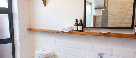 A compact bathroom with a white toilet, a white sink, and a black trash bin.