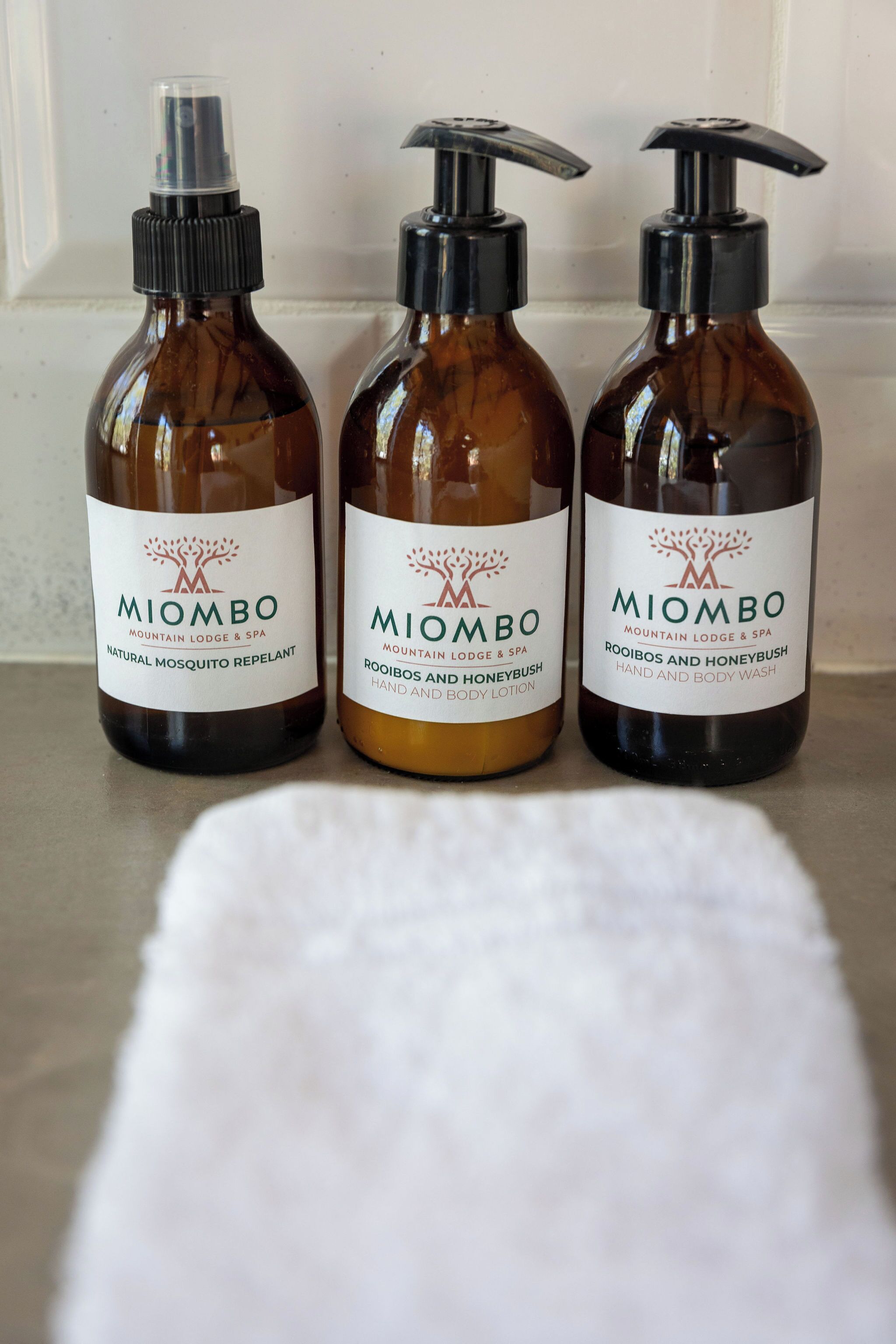 Three bottles of Miombo Mountain Lodge & Spa products on a counter.