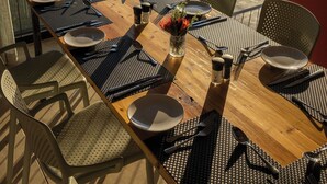 A dining table set with plates, cutlery, and a vase of flowers, overlooking a scenic landscape.