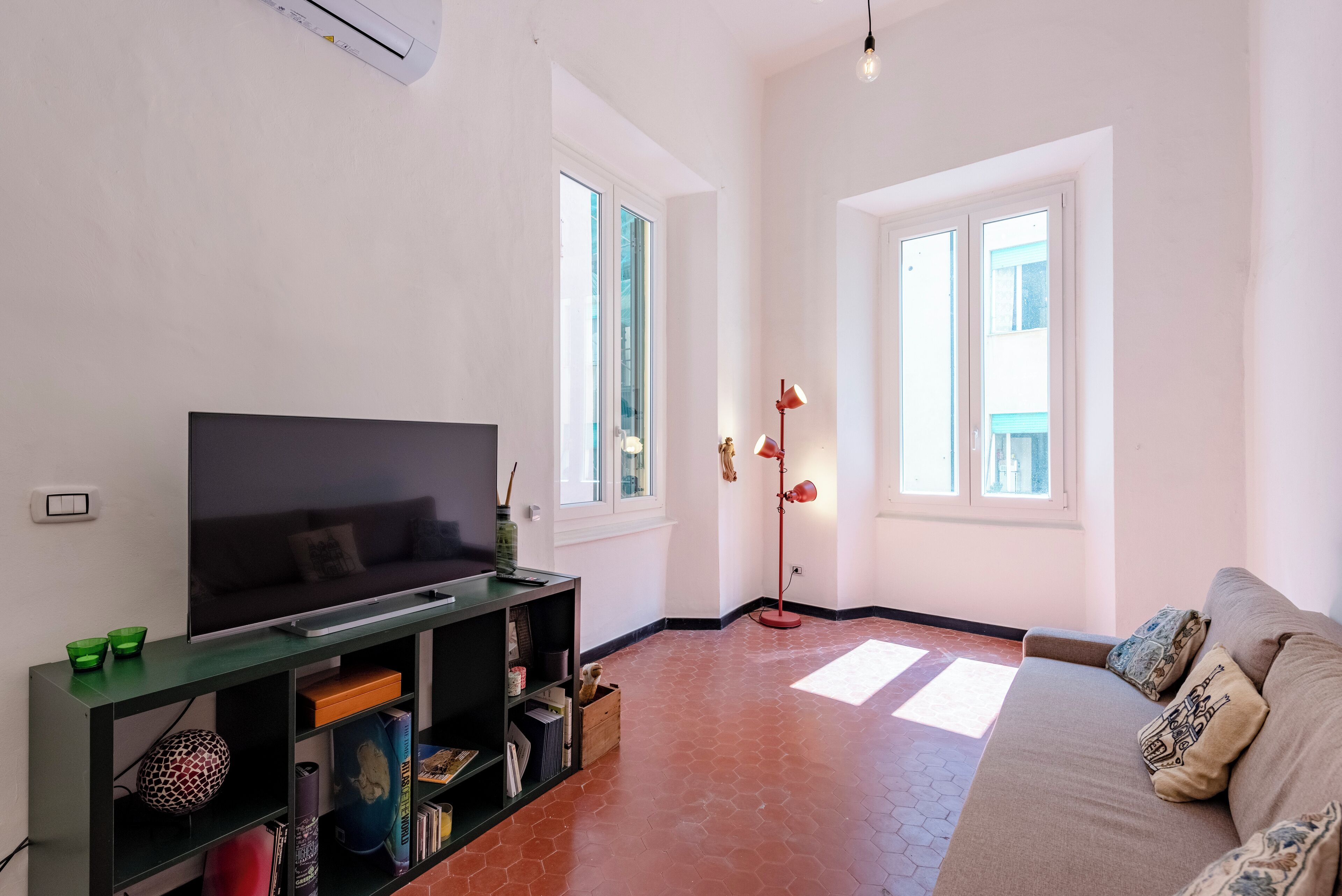 A living room with a flat-screen TV, a bookshelf, a sofa, and a floor lamp.