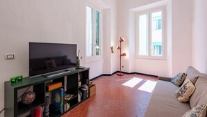 Un salon équipé d’un téléviseur à écran plat, d’une bibliothèque, d’un canapé et d’un lampadaire.