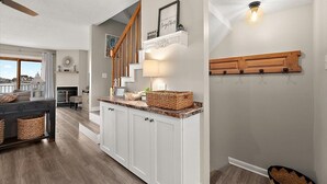 A modern kitchen with white cabinets, a wooden staircase, and a view of the city.