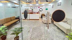 A reception area with a reception desk, sofas, and potted plants. - Breezy Height (New Delhi)