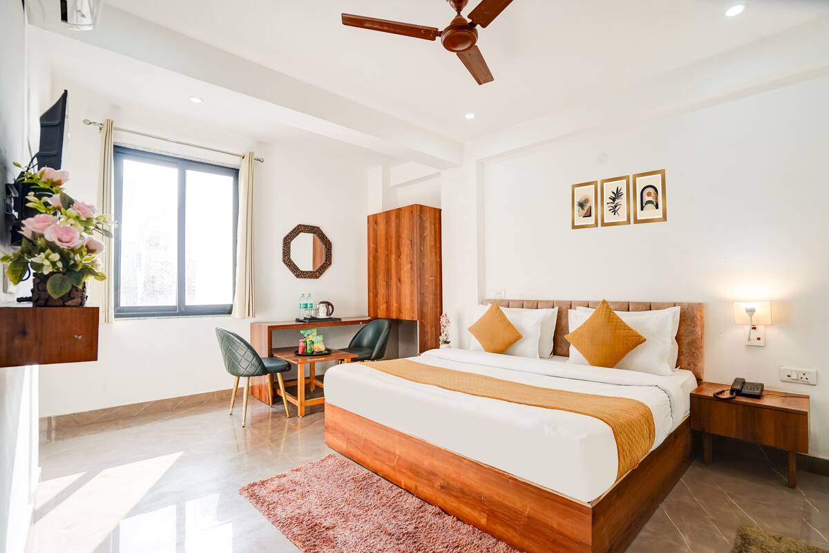 A modern hotel room with a large bed, a desk, a chair, a wardrobe, and a ceiling fan.