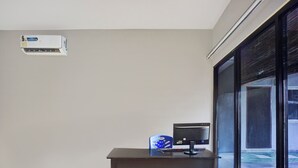 Een kamer met een bureau, een computer en een raam met uitzicht op een zwembad.
