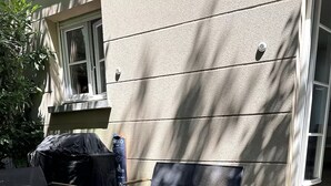 Un'area esterna con posti a sedere, un tavolo, due sedie, un barbecue coperto e un edificio sullo sfondo.