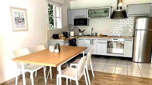 Una cucina moderna con mobili bianchi, un tavolo da pranzo in legno e sedie bianche.
