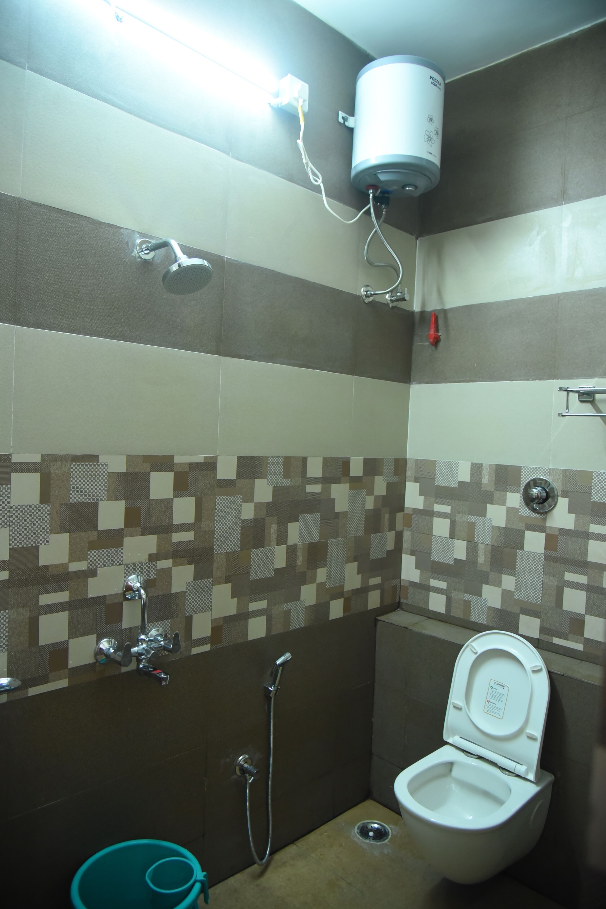 A small bathroom with a toilet, a shower, and a hand dryer.