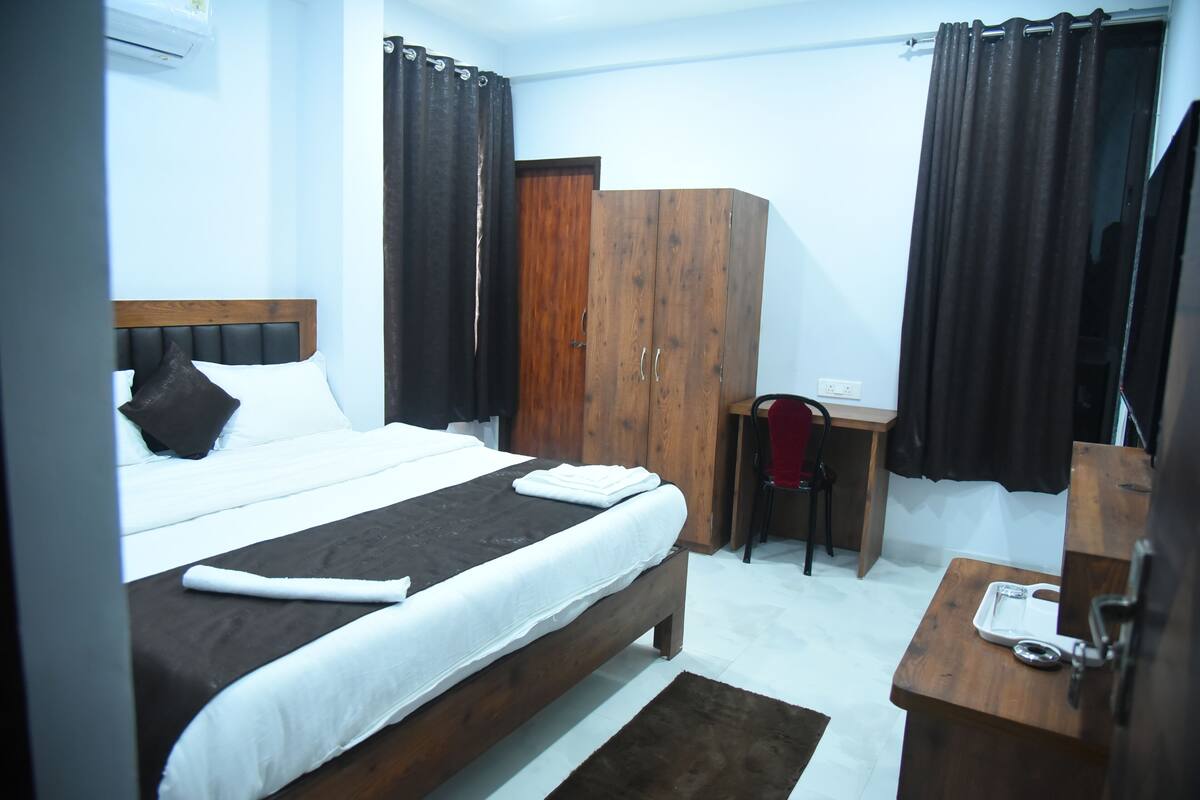 A hotel room with a bed, a desk, a wardrobe, and a mirror.