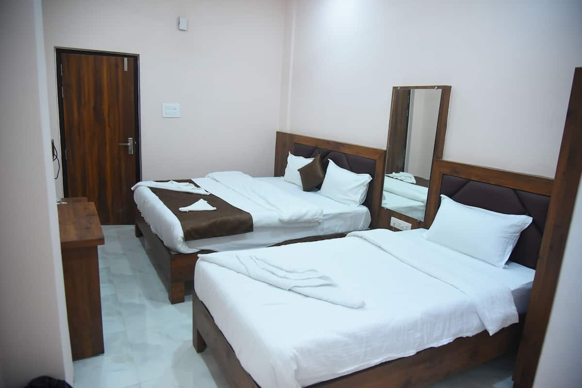 A hotel room with two wooden beds, a wooden nightstand, a mirror, and a door.