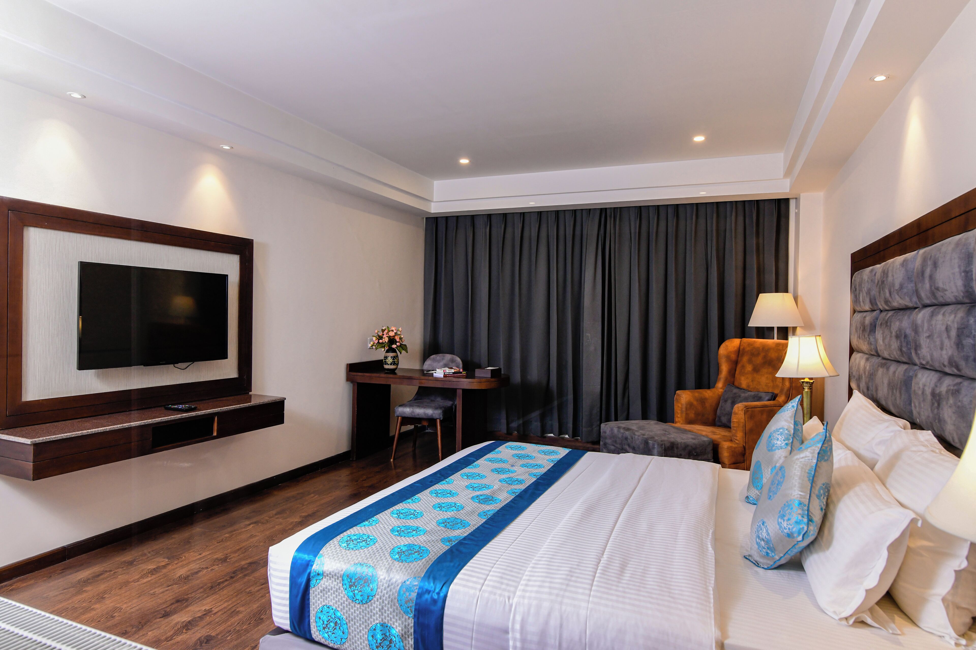 A hotel room with a bed, a desk, a chair, a television, and a window with curtains.
