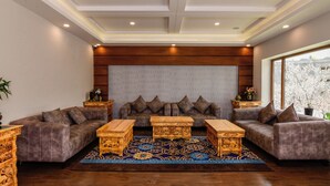 A modern living room with a sectional sofa, two wooden coffee tables, and a patterned rug. - Tsokar Retreat (Leh)