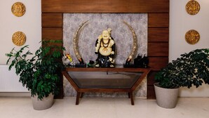 A reception area with a wooden panel wall, a statue, and two potted plants. - Tsokar Retreat (Leh)