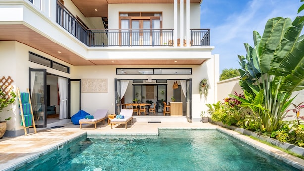 A modern house with a swimming pool, outdoor seating, and lush greenery.