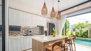 A modern kitchen with a central island, bar stools, and pendant lighting.