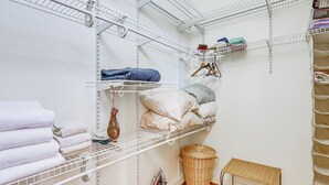 A neatly organized closet with shelves for folded clothes, a wicker basket, and a small table.