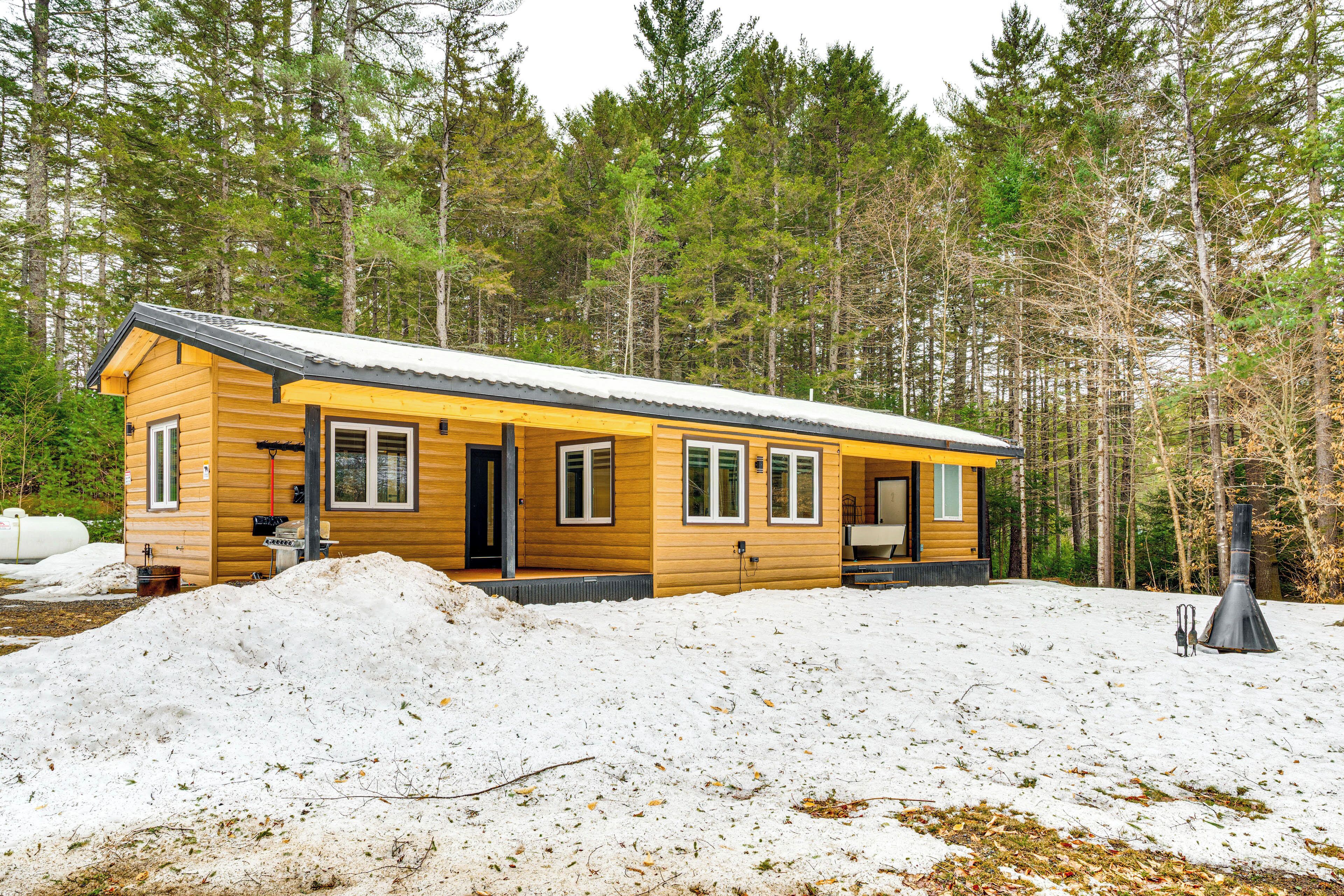 Een houten chalet met grote ramen en een schoorsteen.