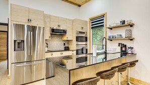 Een moderne keuken met roestvrijstalen apparatuur, houten kastjes en een bar met krukken.