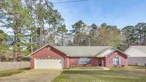 A single-story brick house with a garage, a front lawn, and a wooden fence.