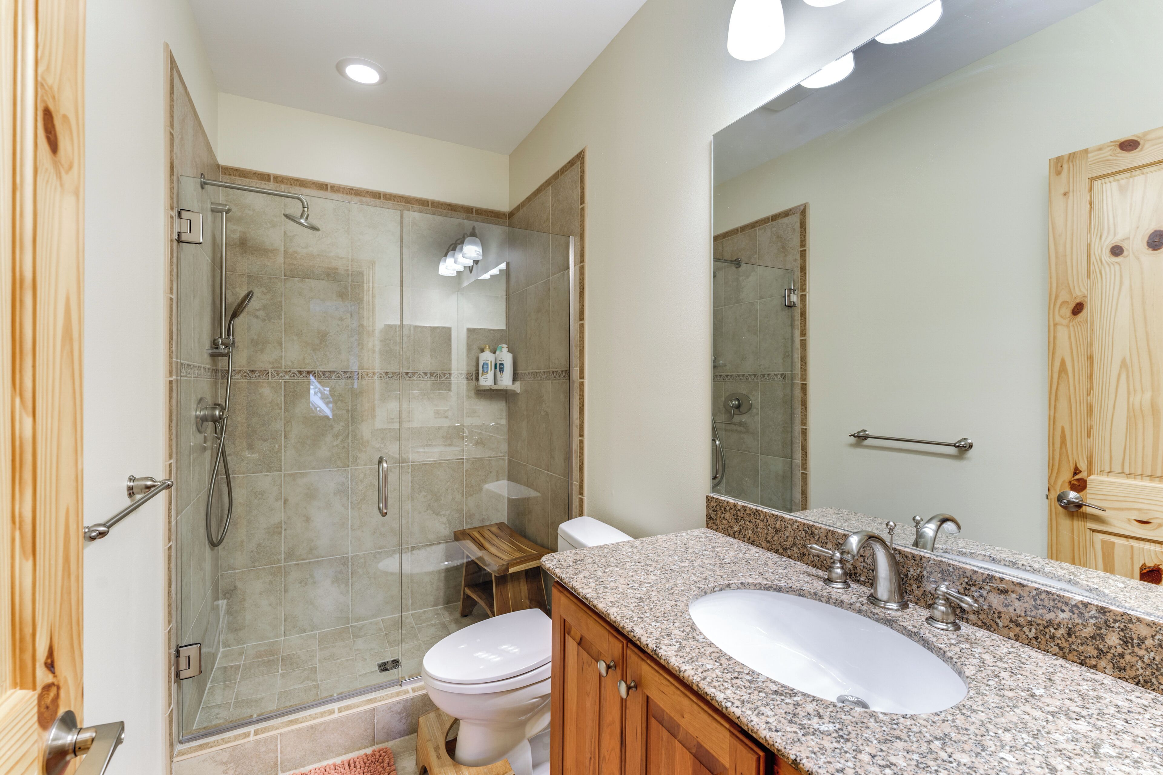 Une salle de bain moderne avec une douche à parois de verre, un meuble-lavabo en bois et un grand miroir.