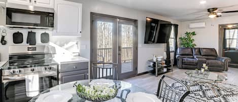 A modern kitchen with stainless steel appliances, a dining area with a glass table, and a living room with a leather sofa.