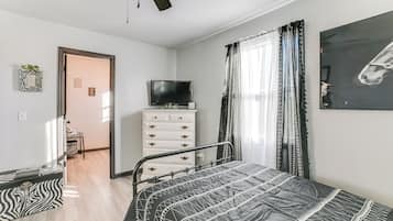 A bedroom with a bed, a TV, a dresser, and a zebra-patterned bench.