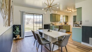 Una cocina moderna con armarios verdes, una isla blanca y un comedor con mesa de mármol y sillas de cuero.