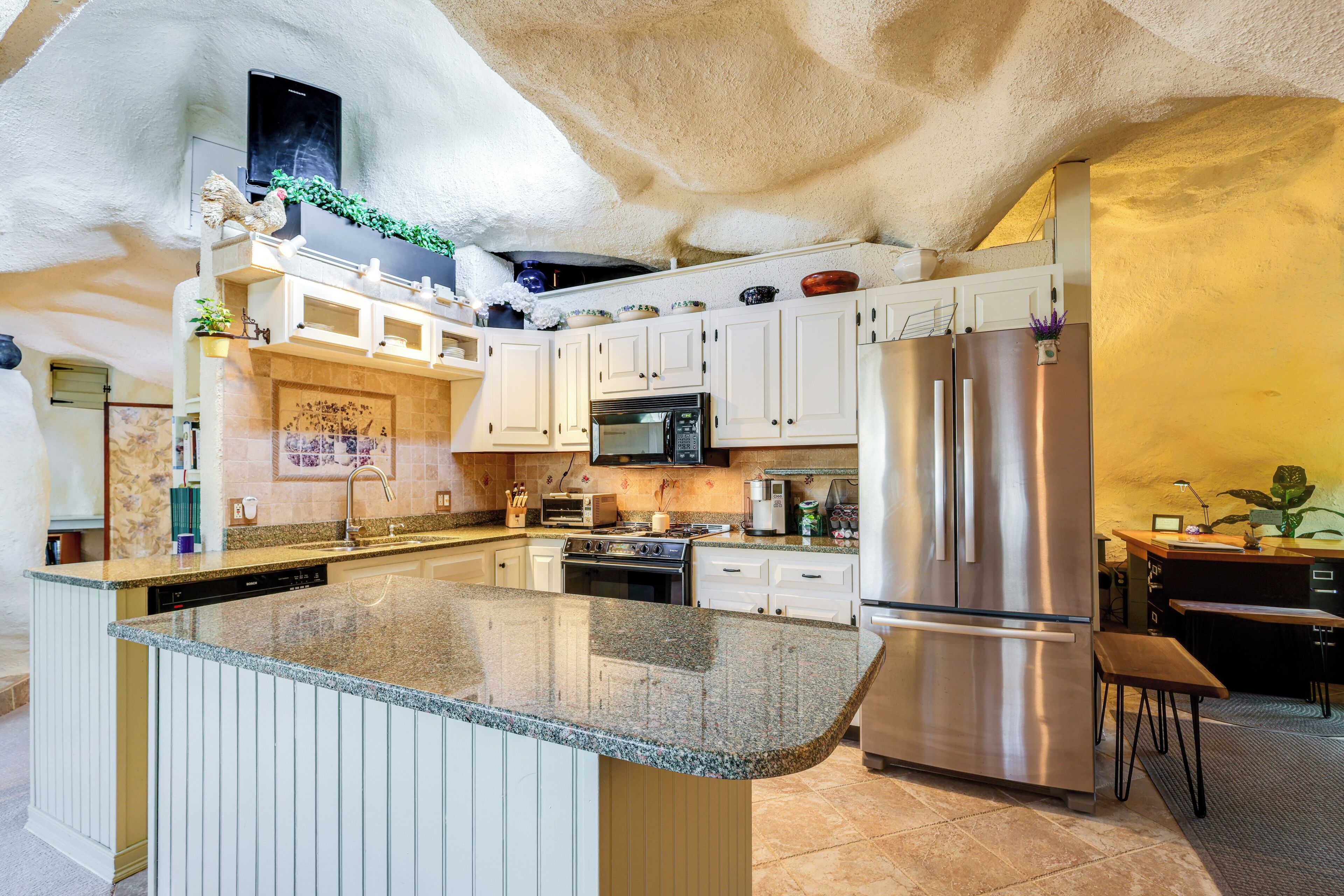 A kitchen with granite countertops, stainless steel appliances, and white cabinetry.