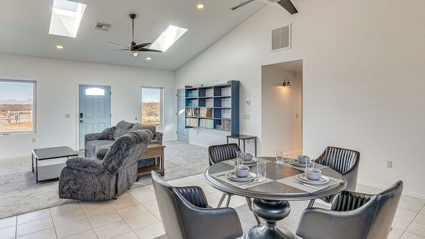A spacious living room with a dining area, a bookshelf, and a ceiling fan.