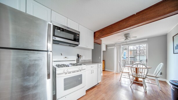 A kitchen with white cabinets, stainless steel appliances, and a dining area with a wooden table and chairs.