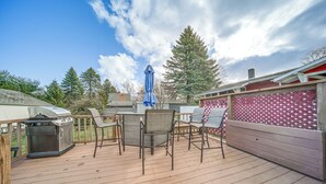 A wooden deck with outdoor furniture, a grill, and a red lattice fence.