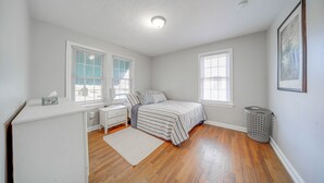 A bedroom with a bed, nightstand, and a window.