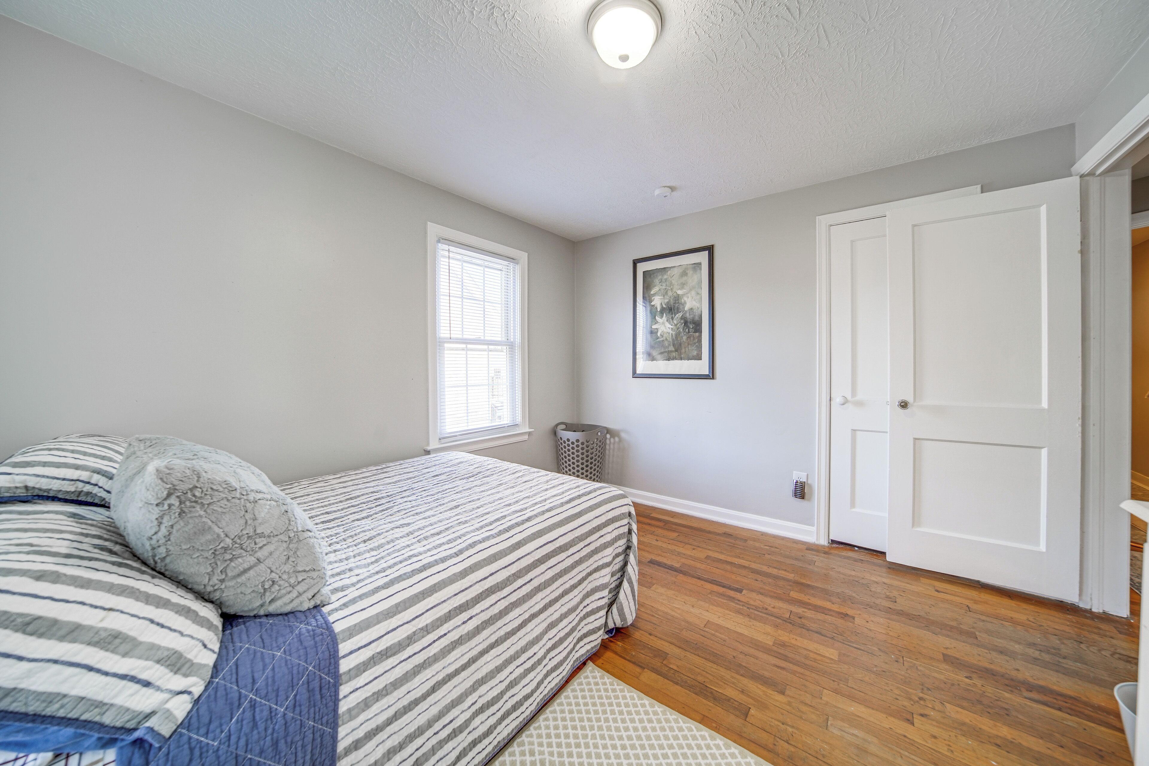 A bedroom with a bed, a window, a door, and a radiator.