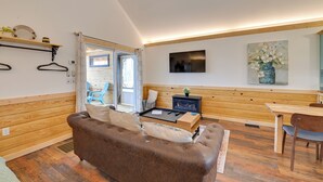 Une pièce chaleureuse avec un canapé en cuir marron, une table à manger en bois et un téléviseur fixé au mur.