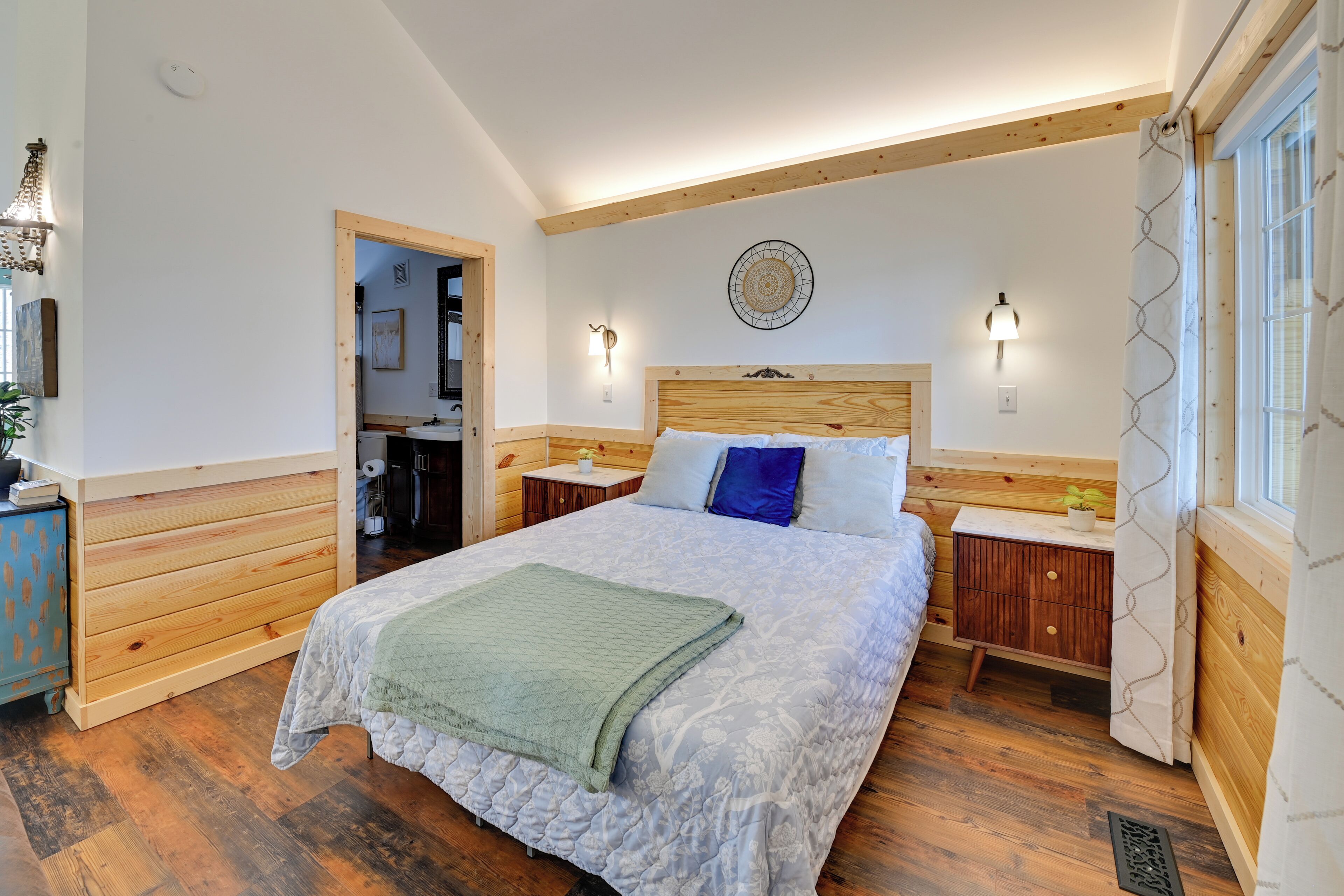 A bedroom with a large bed, wooden headboard, bedside tables, and a nightstand.