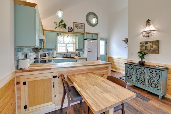 Een keuken met een houten tafel en stoelen, een koelkast en een kast met decoratieve houtsnijwerken.