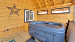 L’intérieur d’un chalet en bois, avec un jacuzzi, des murs en bois et une décoration sur le thème des étoiles.
