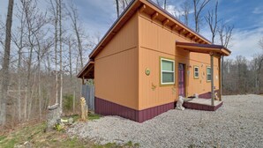 A single-story wooden house with a sloped roof, a front porch, and a gravel driveway. - Plum Crazy: Frenchburg Cabin on 1 Acre (Frenchburg)