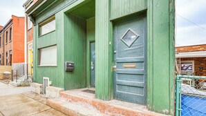 A green building with a metal gate, steps leading to the entrance, and a mailbox on the wall. - Walkable Studio in the Heart of Pittsburgh! (Pittsburgh)