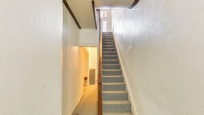 A narrow hallway with a carpeted staircase leading to a door at the end. - Walkable Studio in the Heart of Pittsburgh! (Pittsburgh)