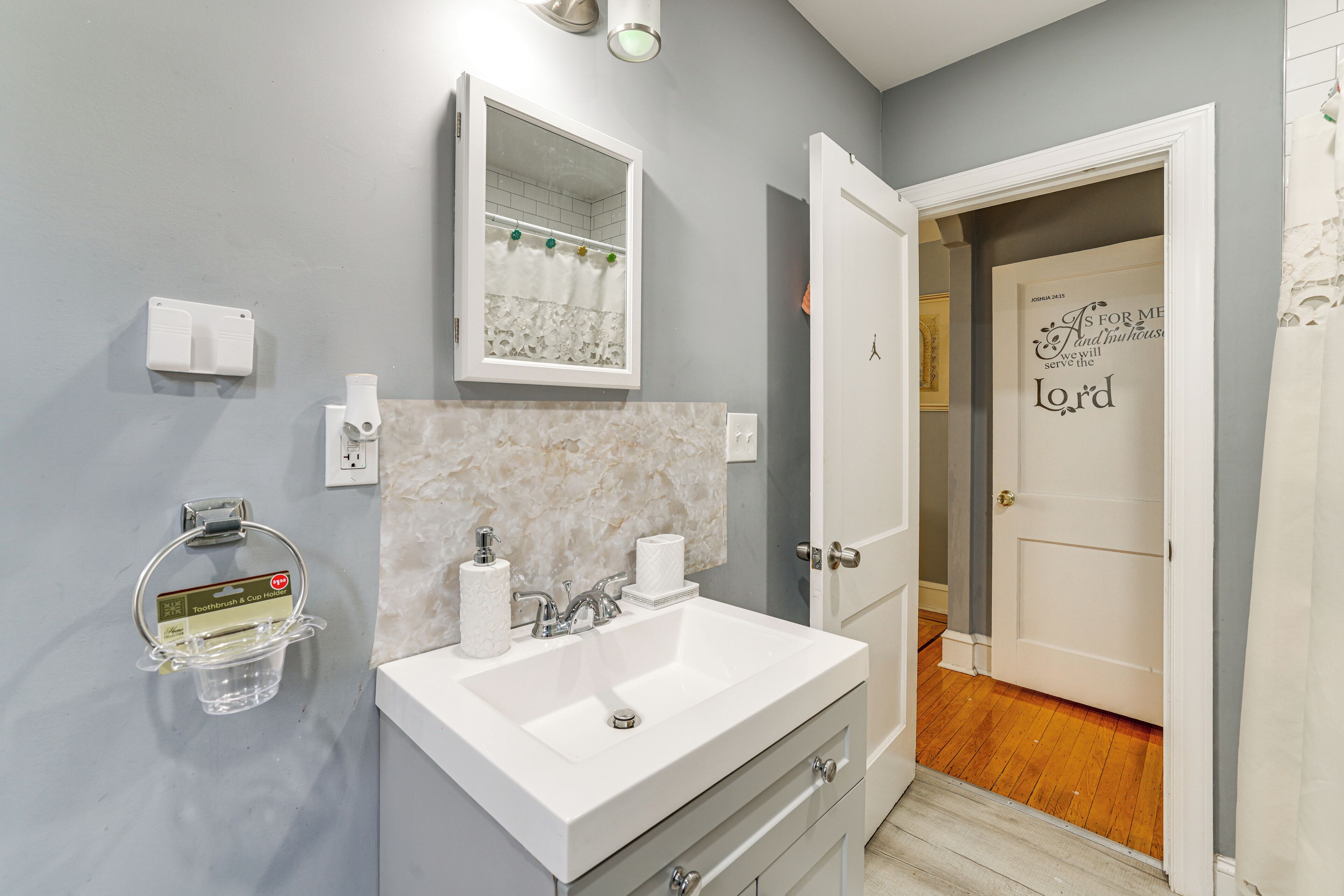 A bathroom with a white sink, mirror, and towel dispenser.
