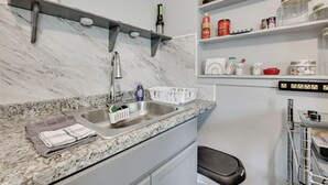 A kitchen with a marble countertop, stainless steel sink, and a built-in oven. There are shelves above the sink holding various kitchen items. - Boat, Hike, & Golf: Inviting Inverness Getaway! (Inverness)