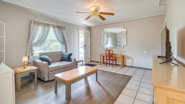 A living room with a sofa, a wooden table, a ceiling fan, a television, and a mirror. - Boat, Hike, & Golf: Inviting Inverness Getaway! (Inverness)