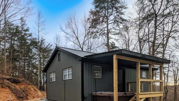 Eine kleine Holzhütte mit Veranda, Tisch und Stühlen vor der Tür.